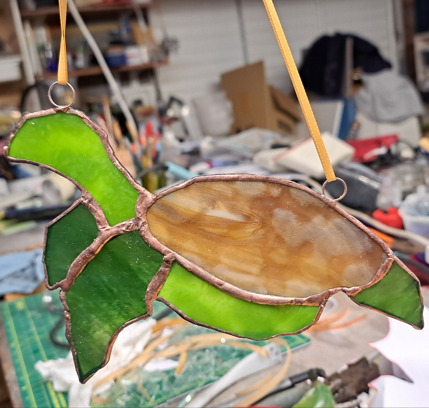 Stained glass turtle cactus hanging in a workshop setting